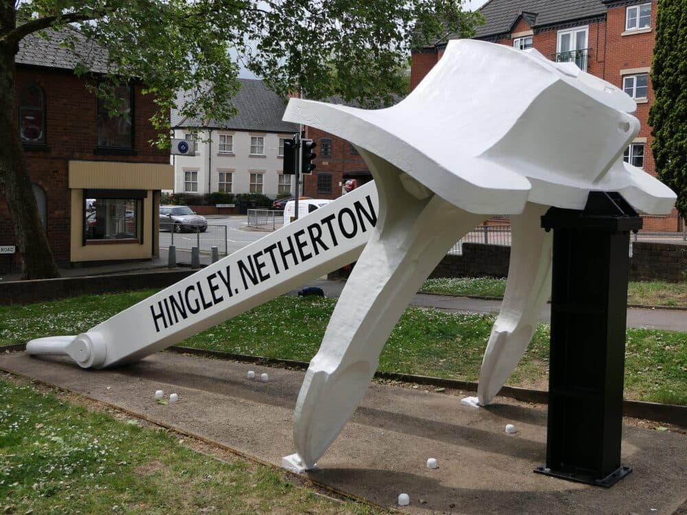 A large white anchor sculpture with "Hingley.Netherton" displayed, located outdoors near a street and buildings. - Home Instead