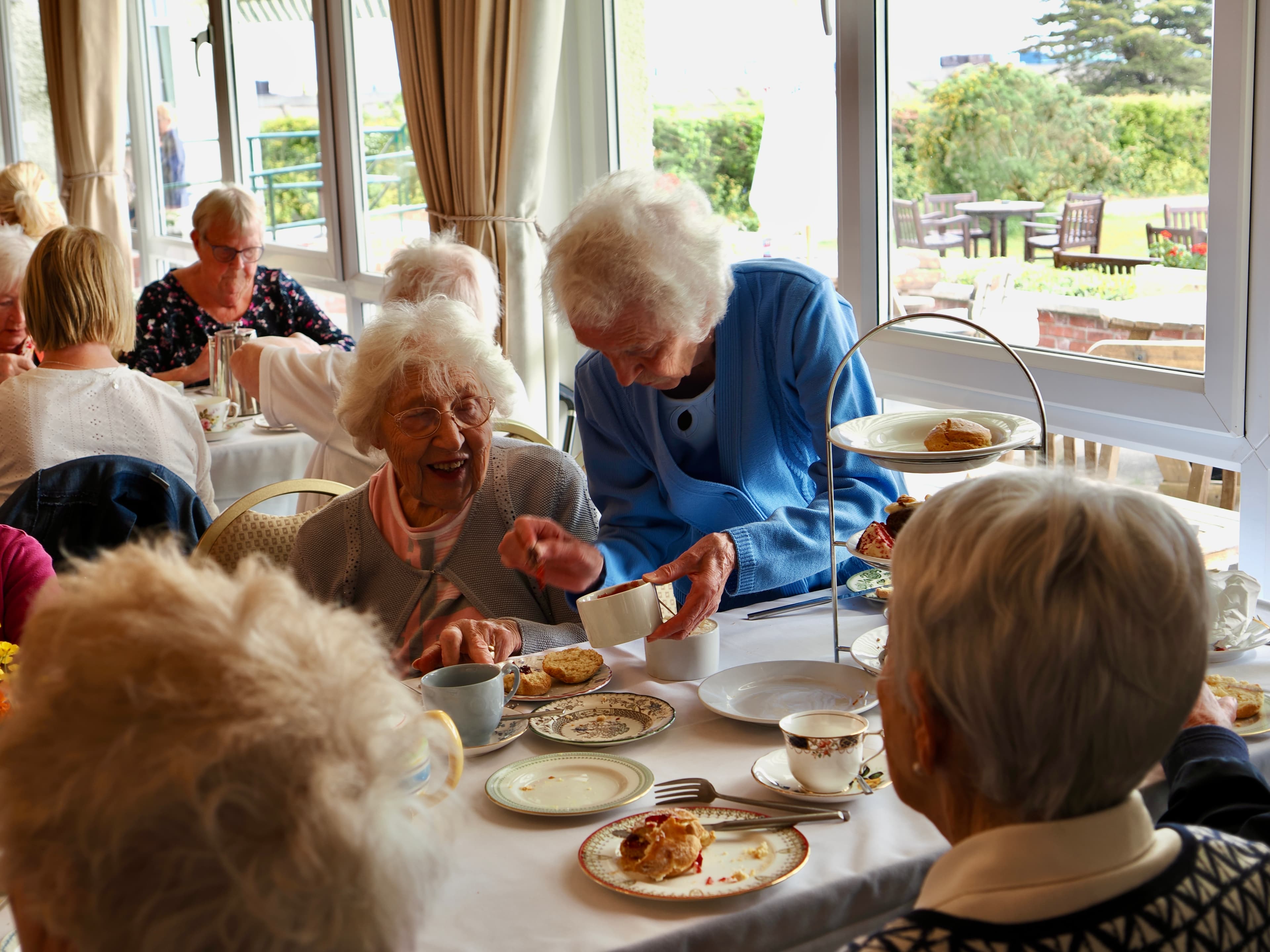 Elderly women enjoying afternoon tea and pastries together at a bright, cheerful tearoom. - Home Instead