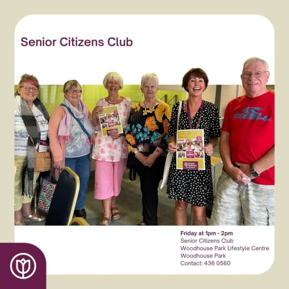 A diverse group of smiling seniors at a club holding flyers. Contact details and venue are listed at the bottom right. - Home Instead