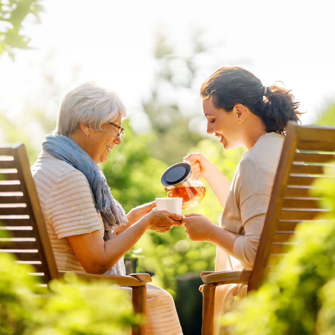 Elderly mum and daughter sitting outdoors talking over a coffee