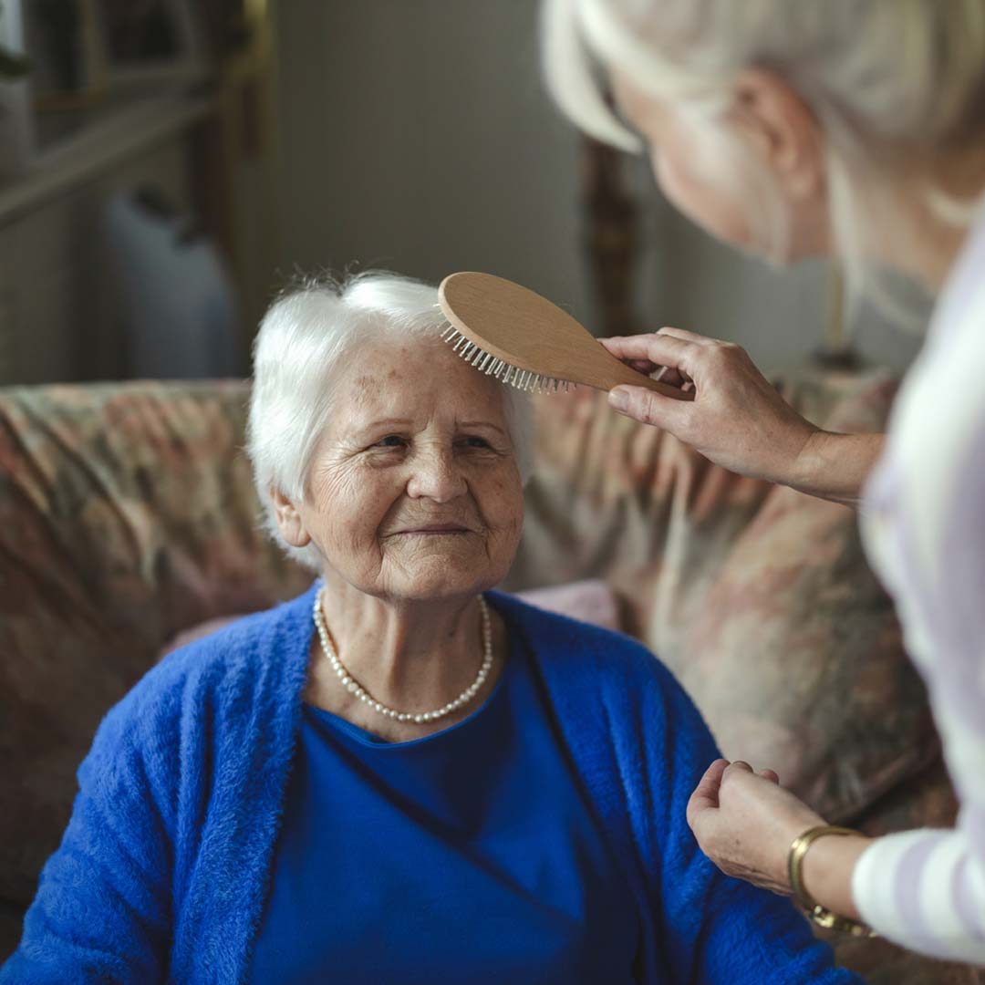 older lady having her hair brushed by a home care professional