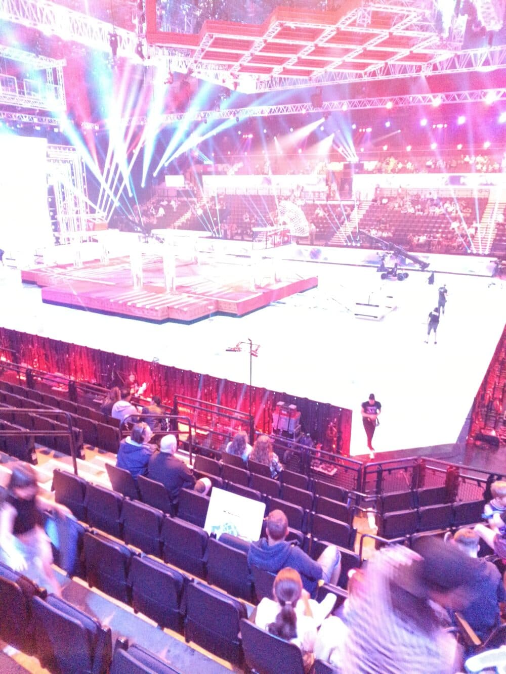 Stage production setup with bright lights and audience seating in a large auditorium, some crew on stage. - Home Instead