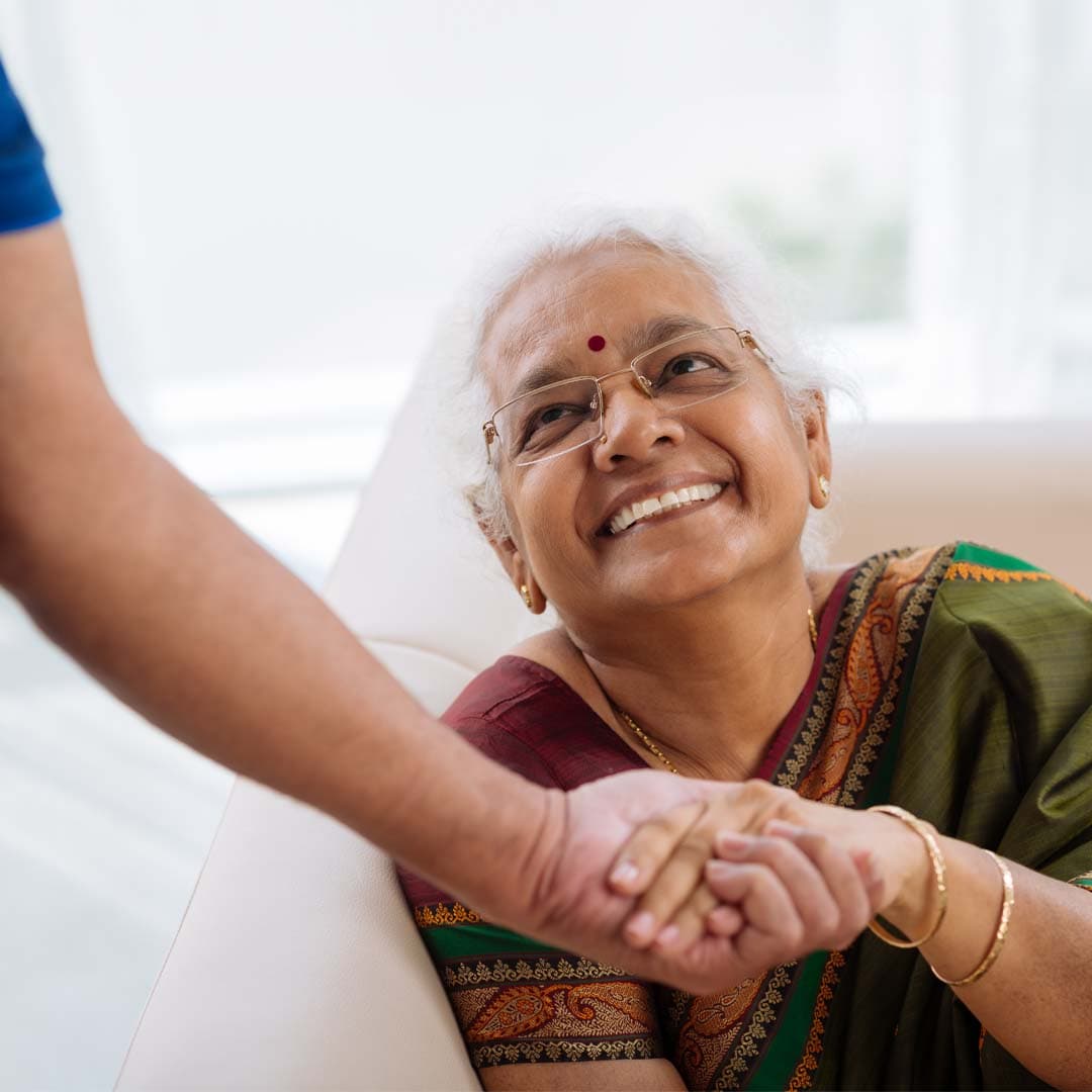senior Indian lady being supported at home by her care professional