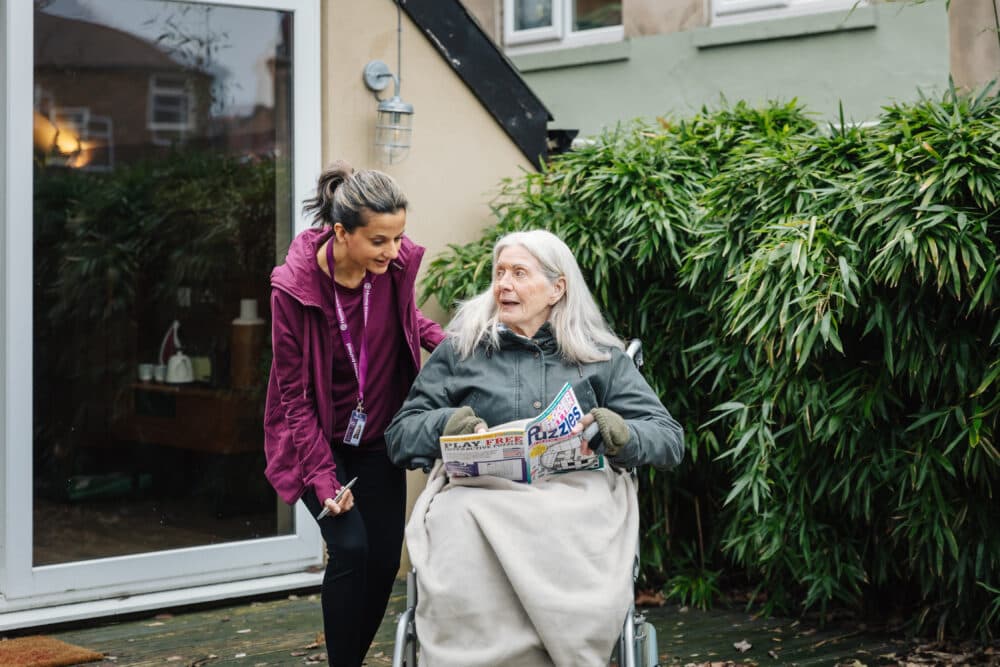 Female client having dementia solving a puzzle and female care pro supporting the client