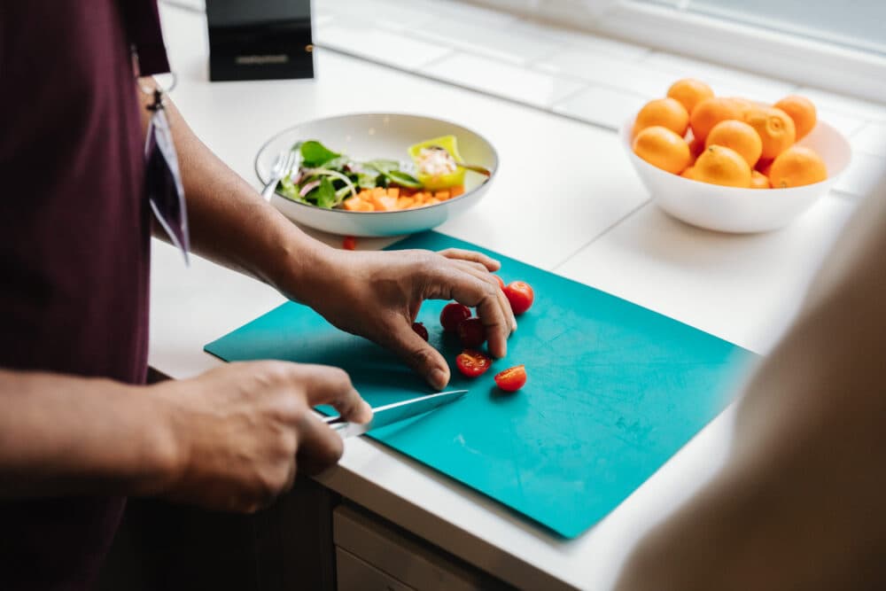 Male carer preparing food - fruit, veg and meat - for this elderly client. - Home Instead