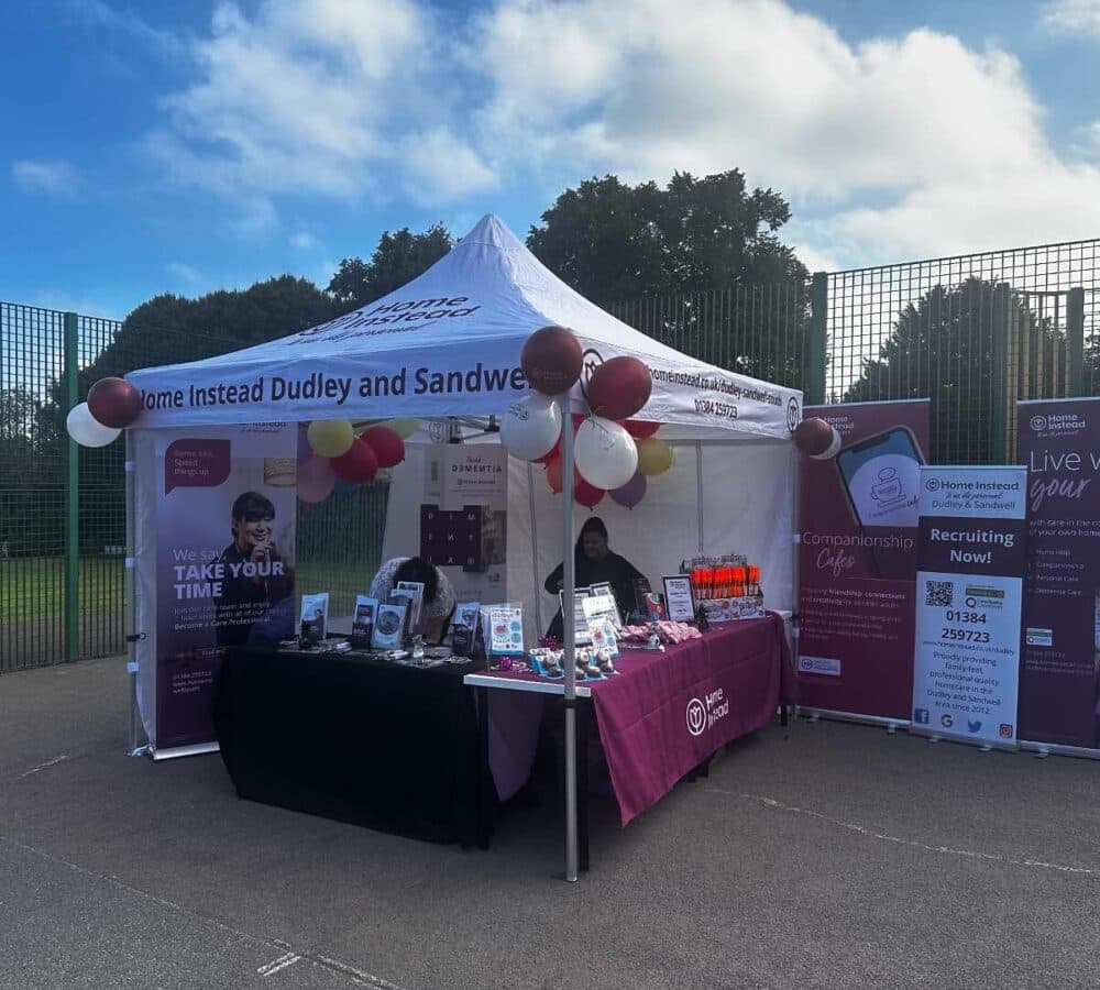 Home Instead Dudley Tent outside in white and maroon colour with a table covered with table cloth with some balloons and banners