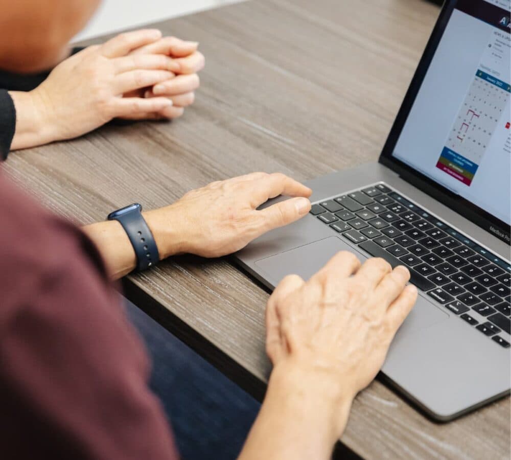 Typing to an Apple silve rlatop and black keyboard