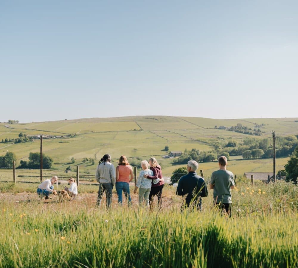 People walking together in a bushy field with a beautiful landscape view