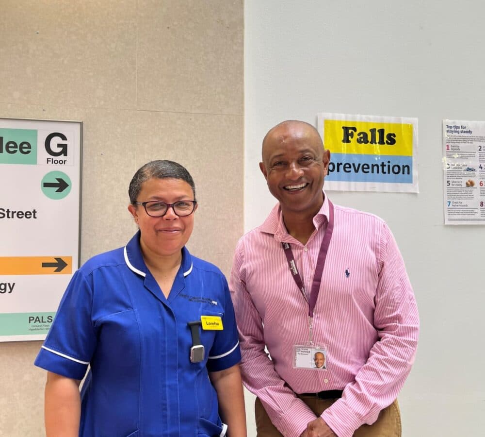 Loreta, a nurse wearing a blue uniform with Tony, standing inside the hospital and both are smiling