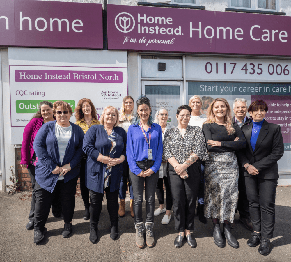 Home Instead Bristol North team happy together and smiling outside their Home Instead office