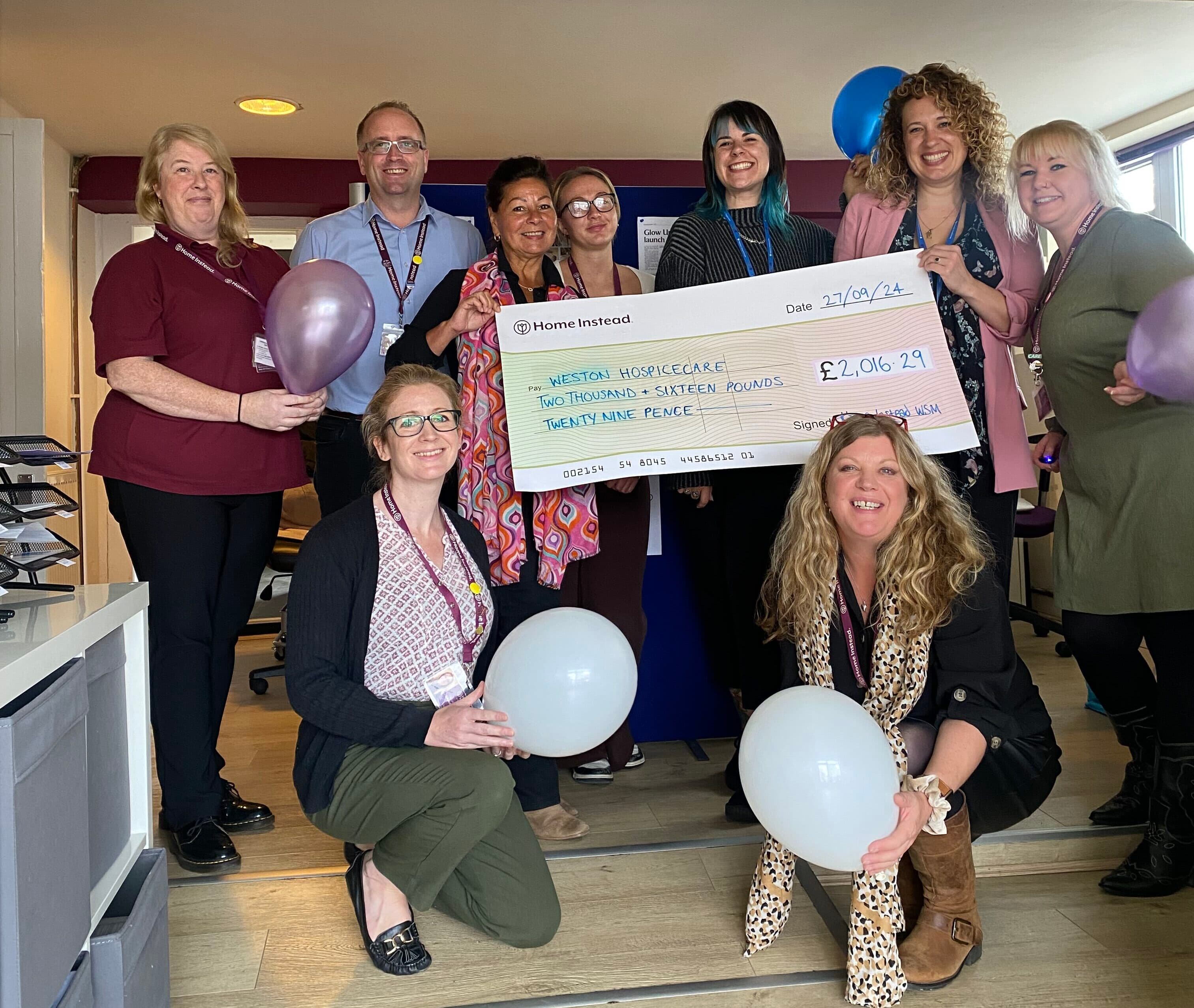 Staff from Home Instead Weston super Mare presenting Weston Hospicecare staff with a novelty sized cheque for £2,016