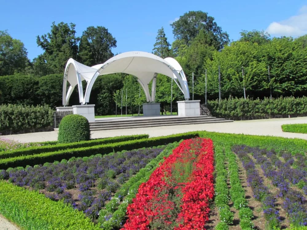 Garden with colorful flower beds and a white, modern canopy structure in the background. - Home Instead