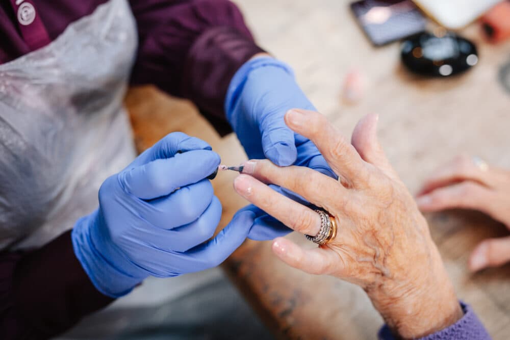 Female Care Pro applying nail paint for female client
