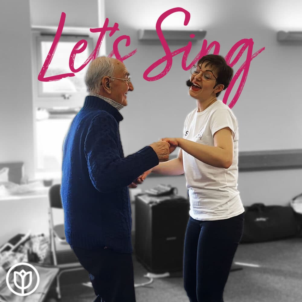 An elderly man and a young woman happily sing and dance together in a room. "Let's Sing" is written in pink text above them. - Home Instead