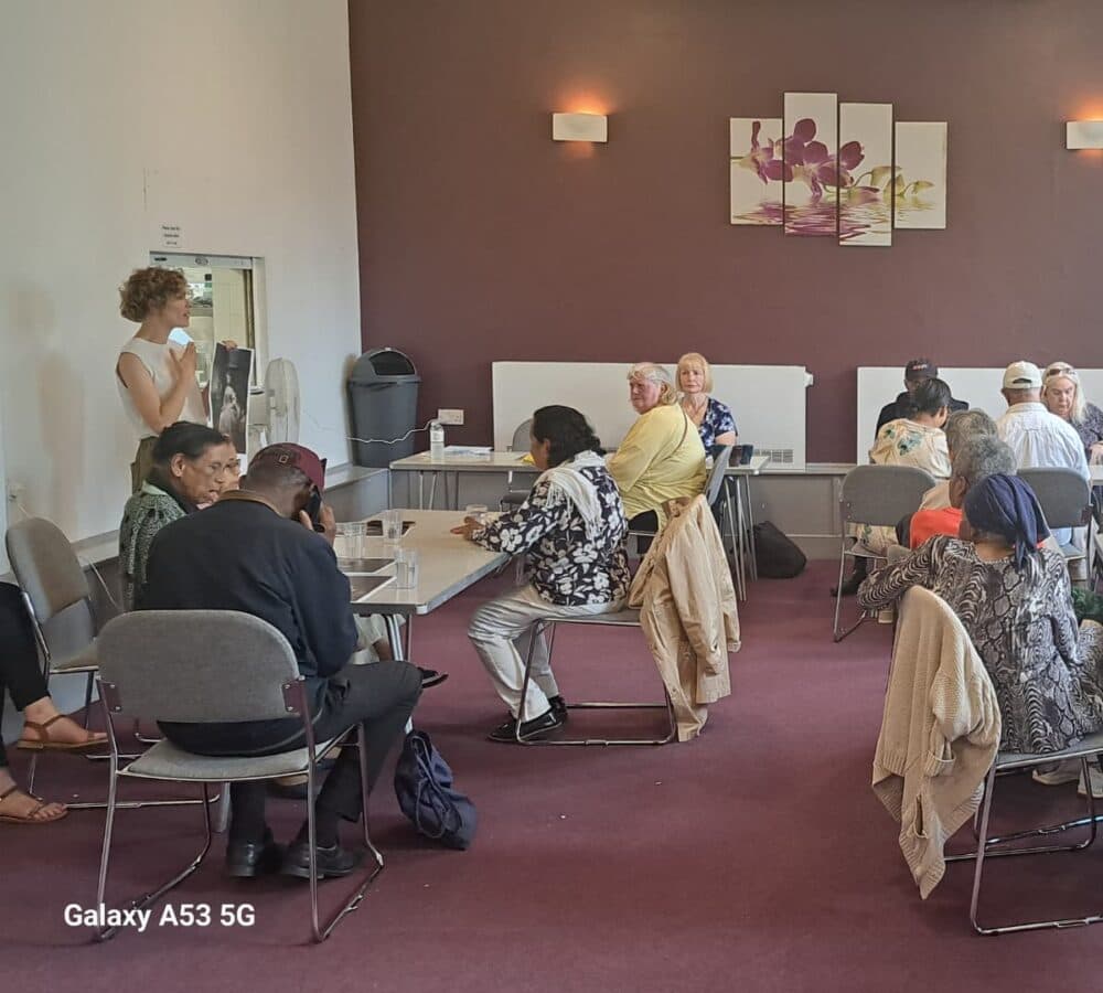 Group of seniors listening and sitting inside a room with an instructor