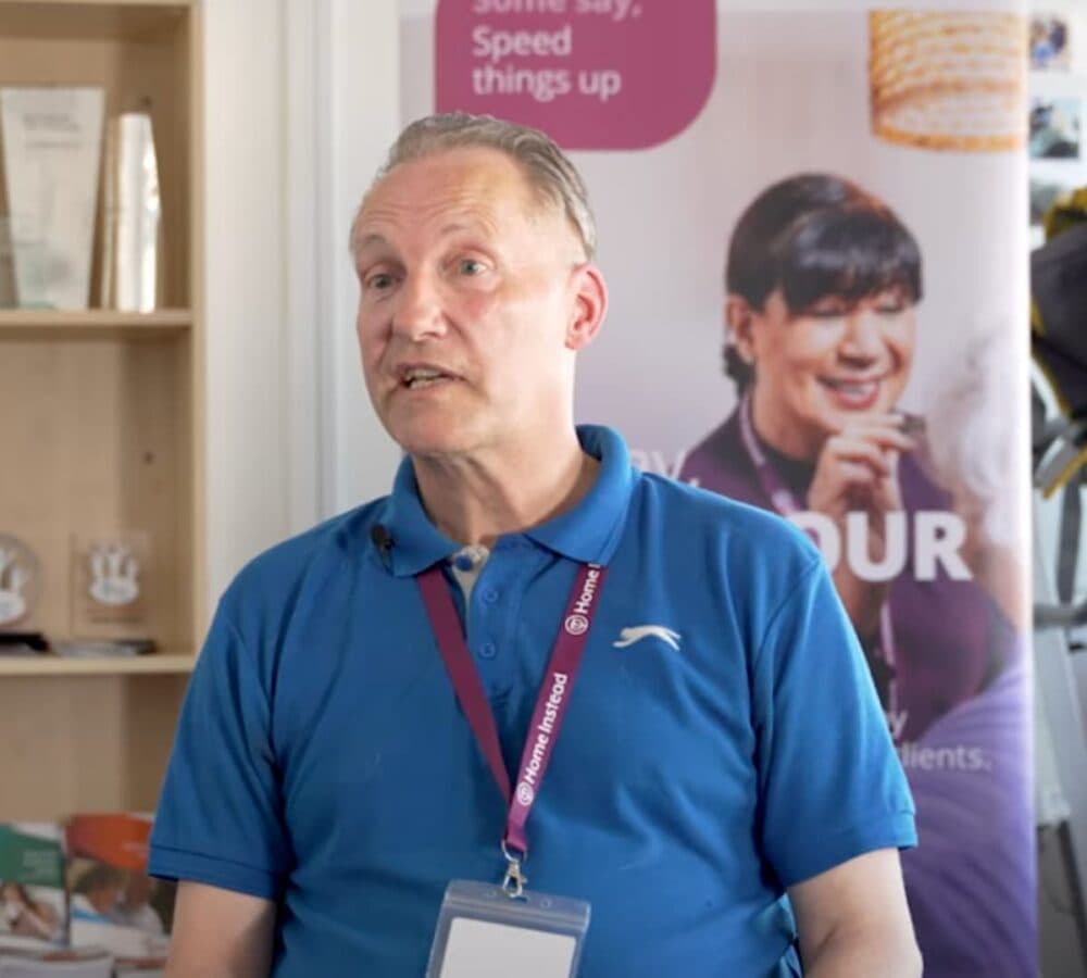 A male carer inside Home Instead office wearing a blue shirt with ID