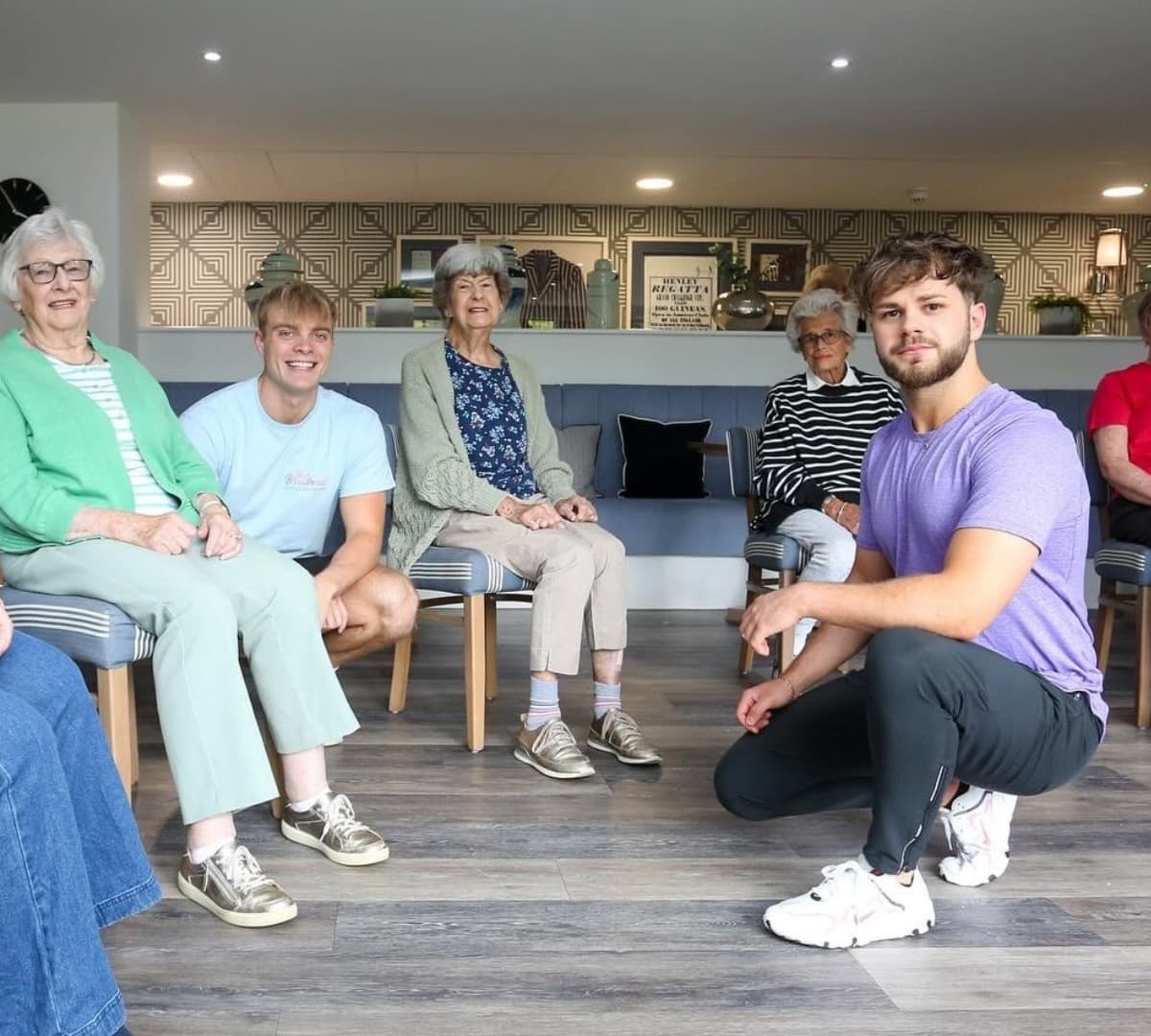 Men and older adults sitting and smiling inside a room and wearing rubber shoes
