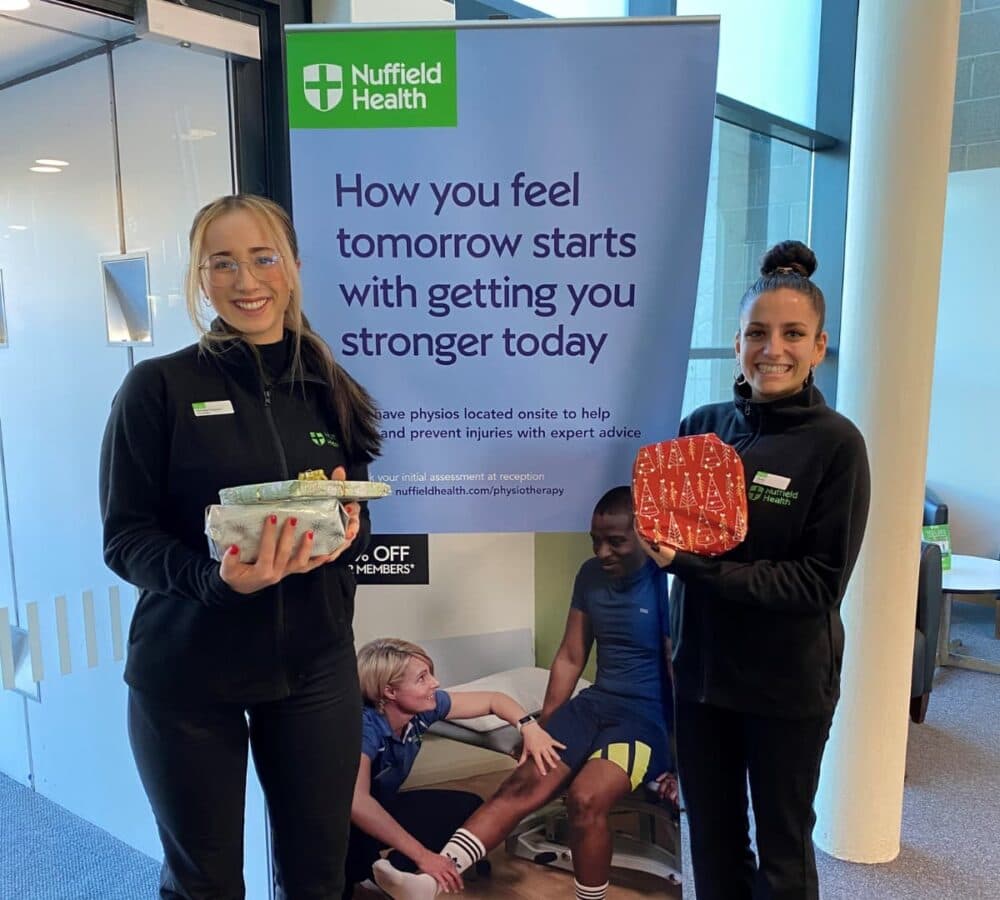Two women standing and holding gifts while smiling and showing a happy to face