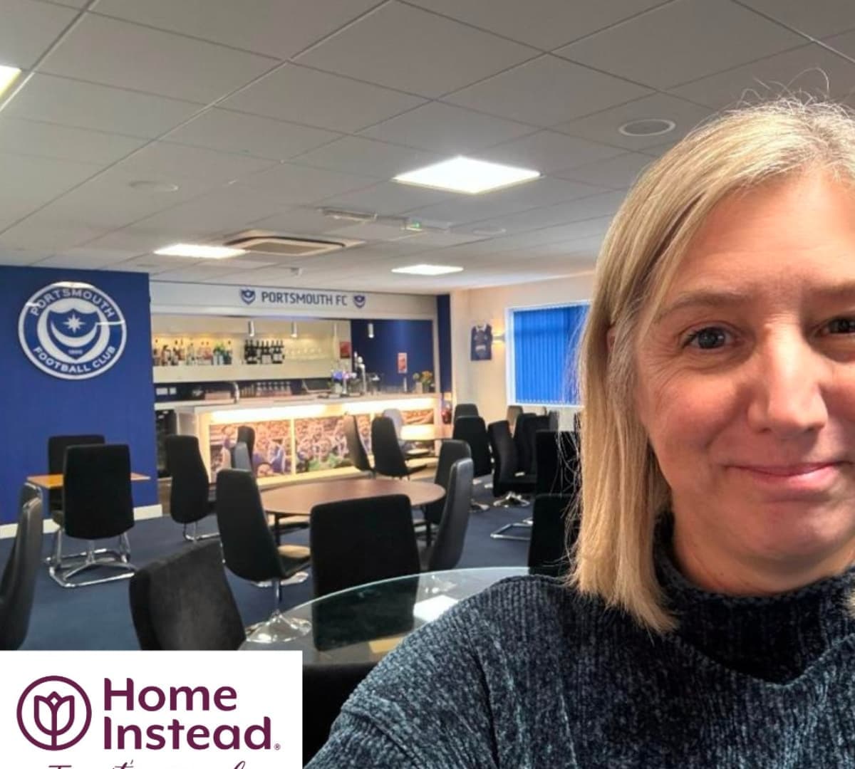 Woman smiling with short hair while insidte the Portsmouth FC with many chairs and tables at the background