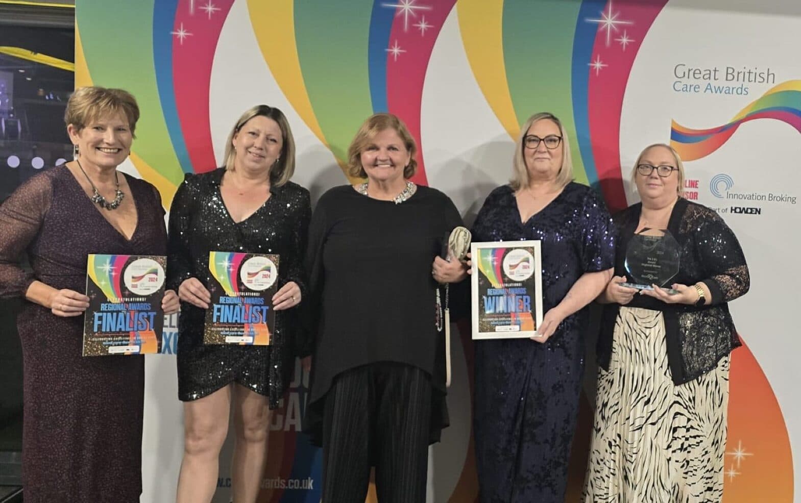 Five women dressed formally hold certificates and trophies at the Great British Care Awards event. - Home Instead