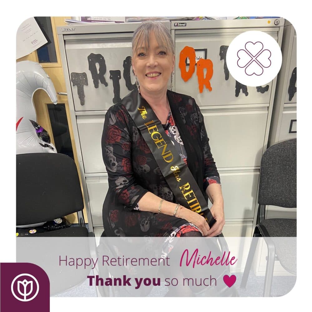 Smiling woman wearing a "The Legend Has Retired" sash at a retirement celebration for Michelle. - Home Instead