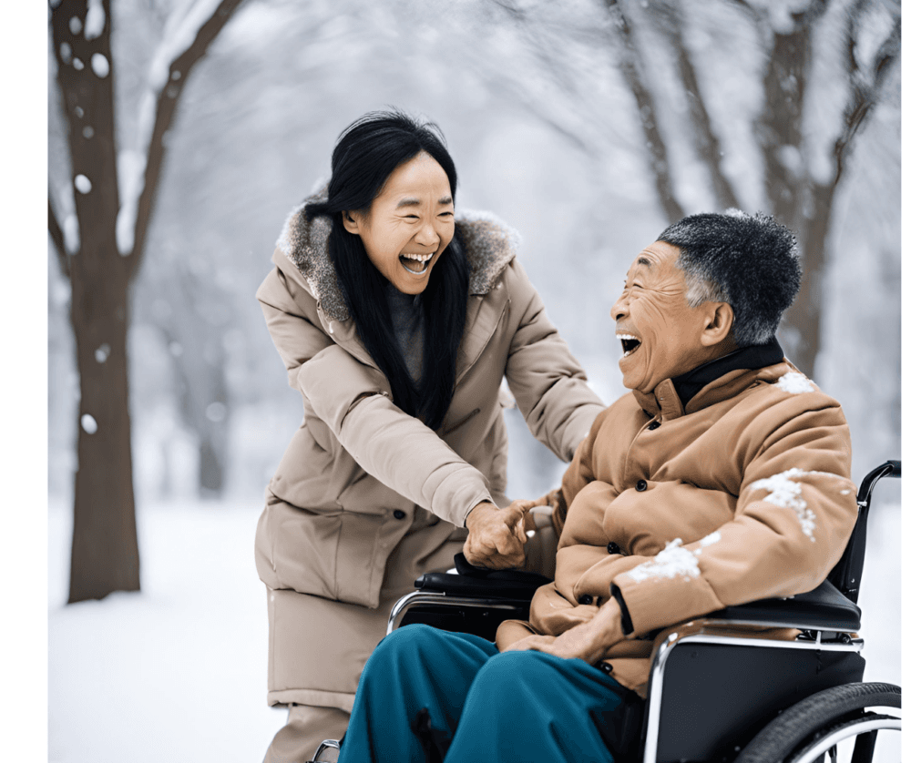A woman and an elderly man in a wheelchair share a joyful moment outside in a snowy park. - Home Instead