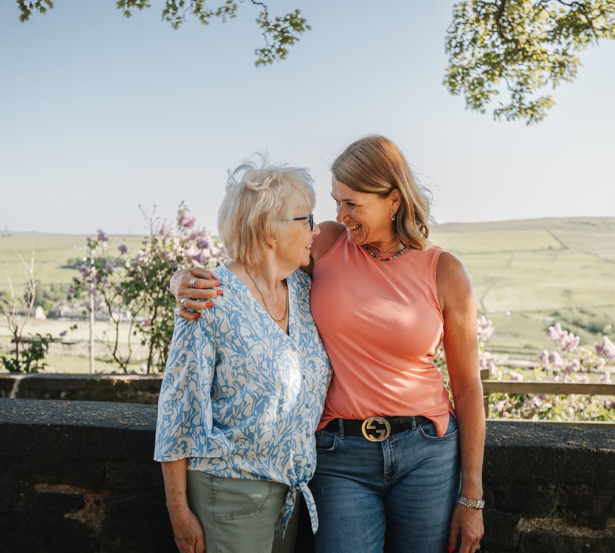 Two women looking at each other both happy outside the field with a beautiful view