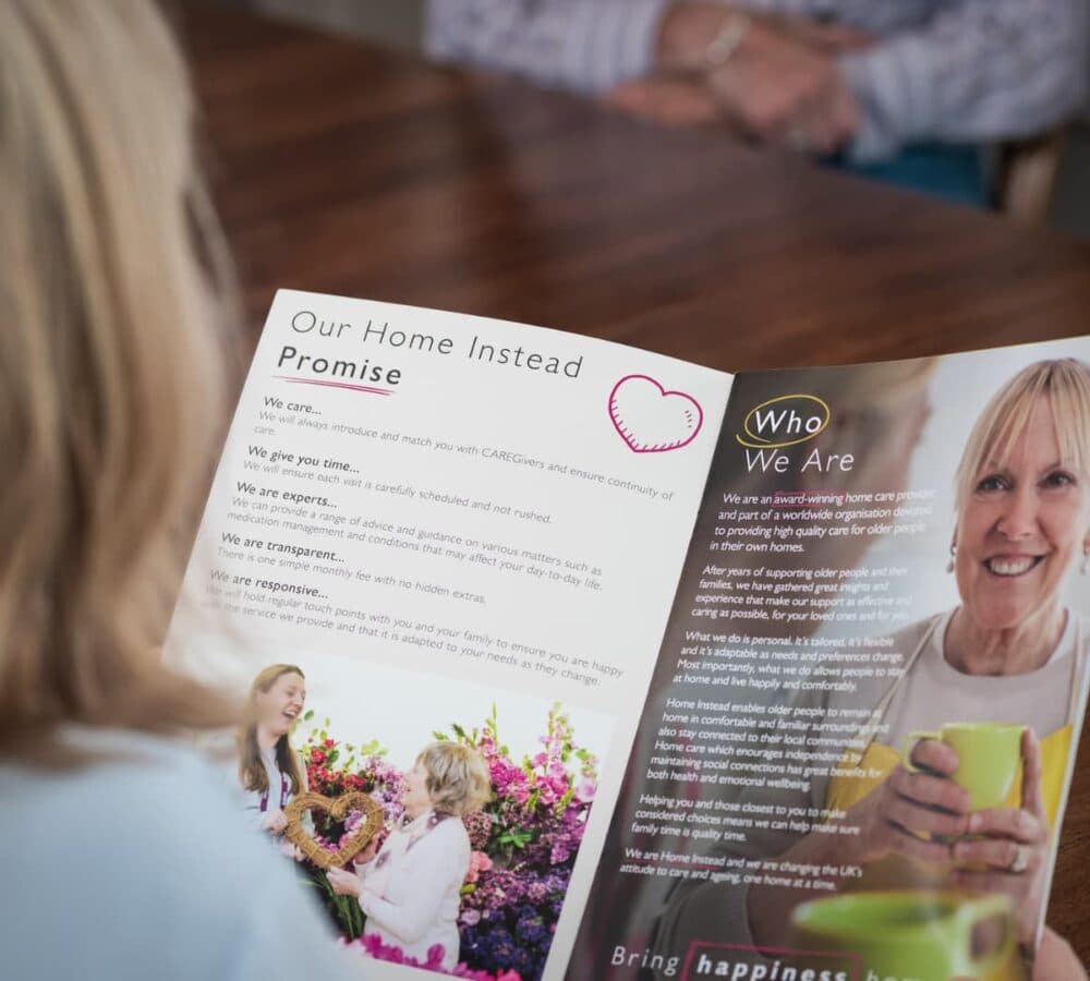 Home Instead brochure being read with Home Instead Promise and Who we are with a photo of a lady