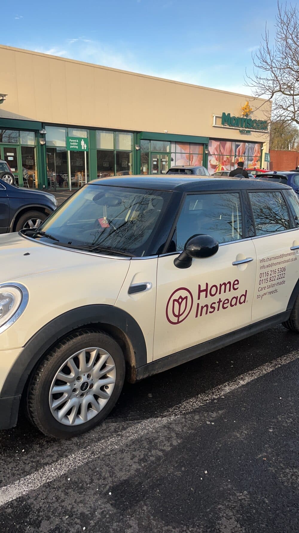 A Home Instead car parked in front of a Morrisons supermarket on a sunny day. - Home Instead