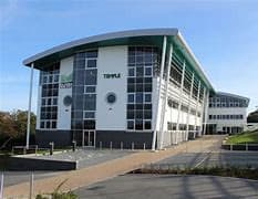 Modern three-story college building with large glass windows and a curved roof under a blue sky. - Home Instead