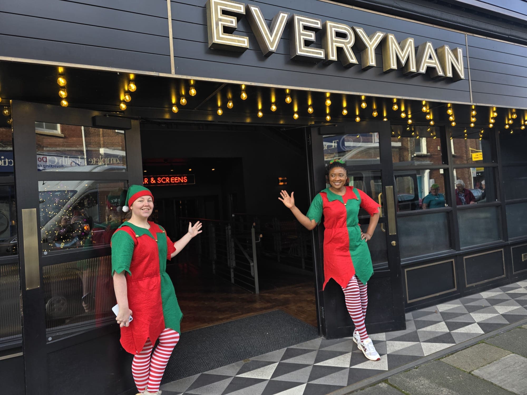 Two eleves outside the Everyman cinema welcoming people in
