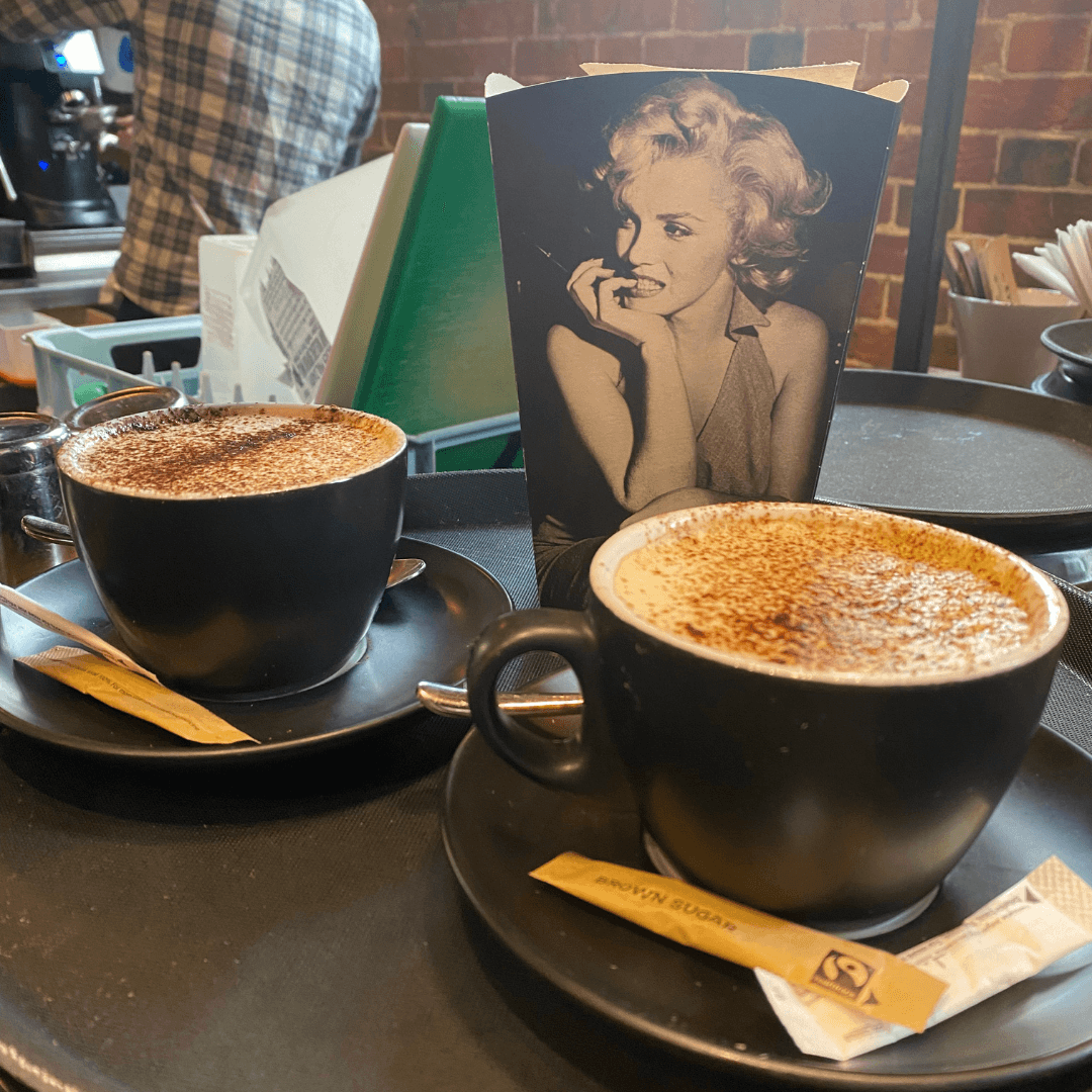 A cosy setting featuring cappuccino coffees and a bowl of popcorn on a table at Everyman Cinema in Winchester. The image highlights the welcoming ambiance for a free dementia-friendly morning matinee event.