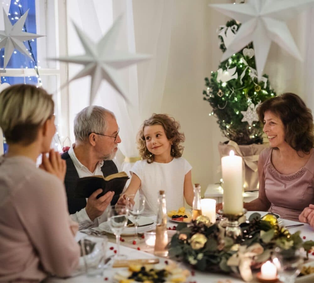 Family having dinner at home with food on the table and a christmas tree and a star decoration on the window