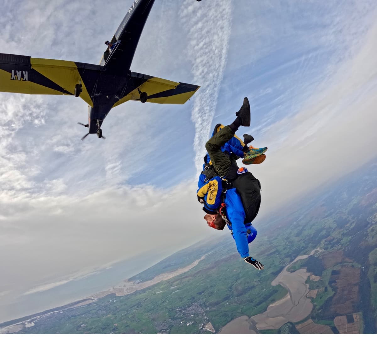 Woman umping off the plane with a coach on a clear blue sky