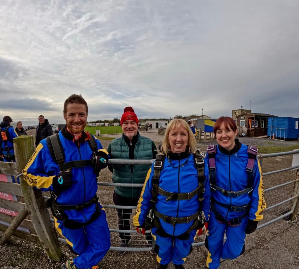 Two men and two women out on a field wearing blue all smiling and happy