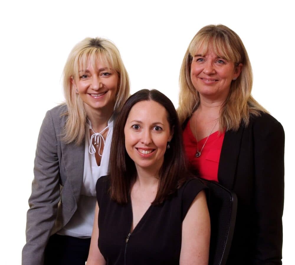 Three women wearing formal clothes and all smiling