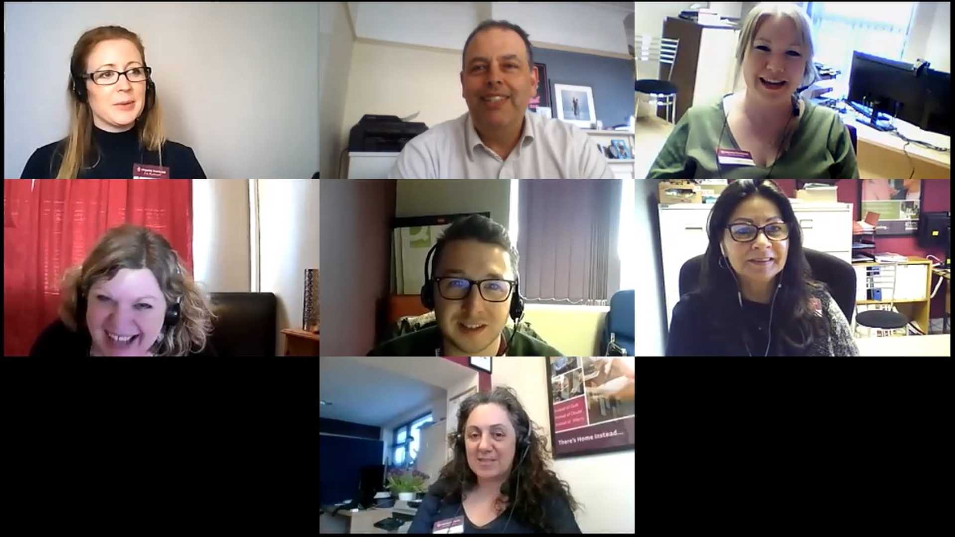 A group of seven people smiling during a video conference call, each in their own separate window. - Home Instead
