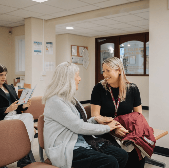 An older lady and her care professional in a hospital waiting room