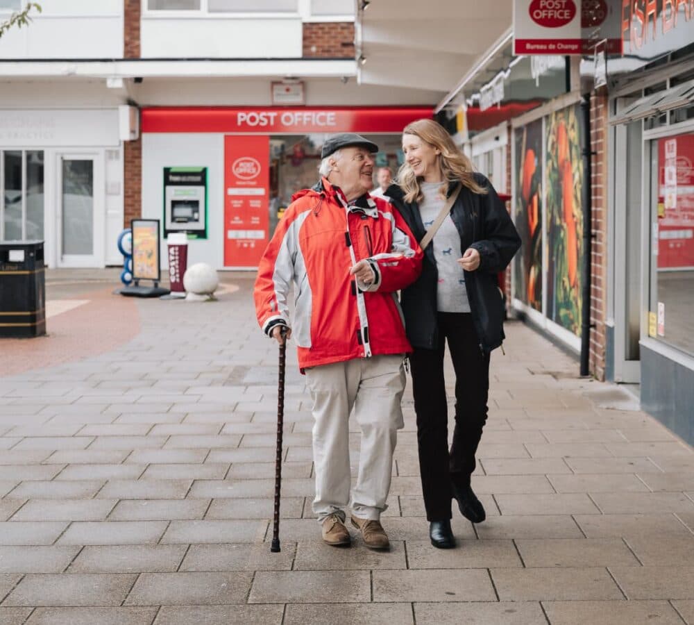 An old man wearing a hat with his daughter walking utdoors