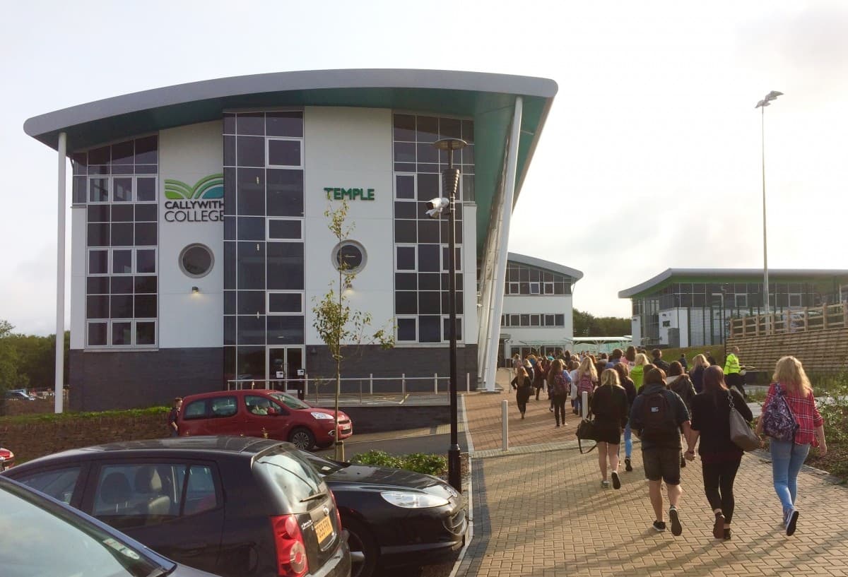 Students walk toward the main entrance of Callywith College, a modern building with large windows. - Home Instead