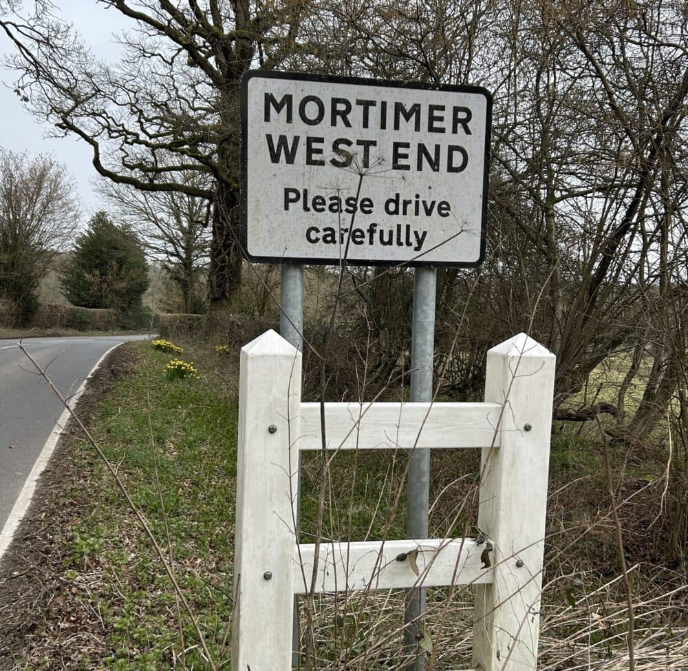 Roadside sign as you come into the village announcing Mortimer West End and asking drivers to drive carefully