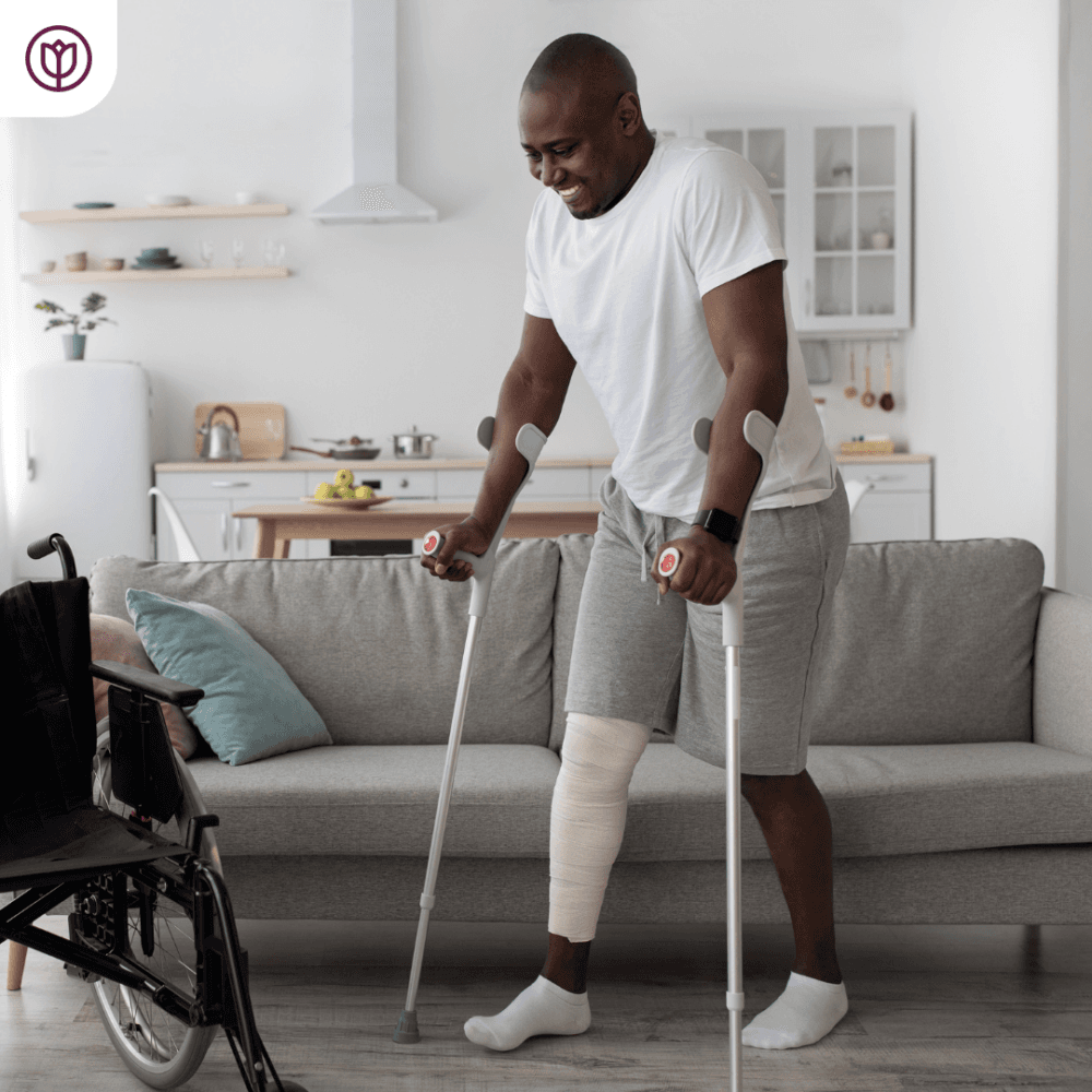 Young man on crutches after knee surgery, with wheelchair - home care with Home instead