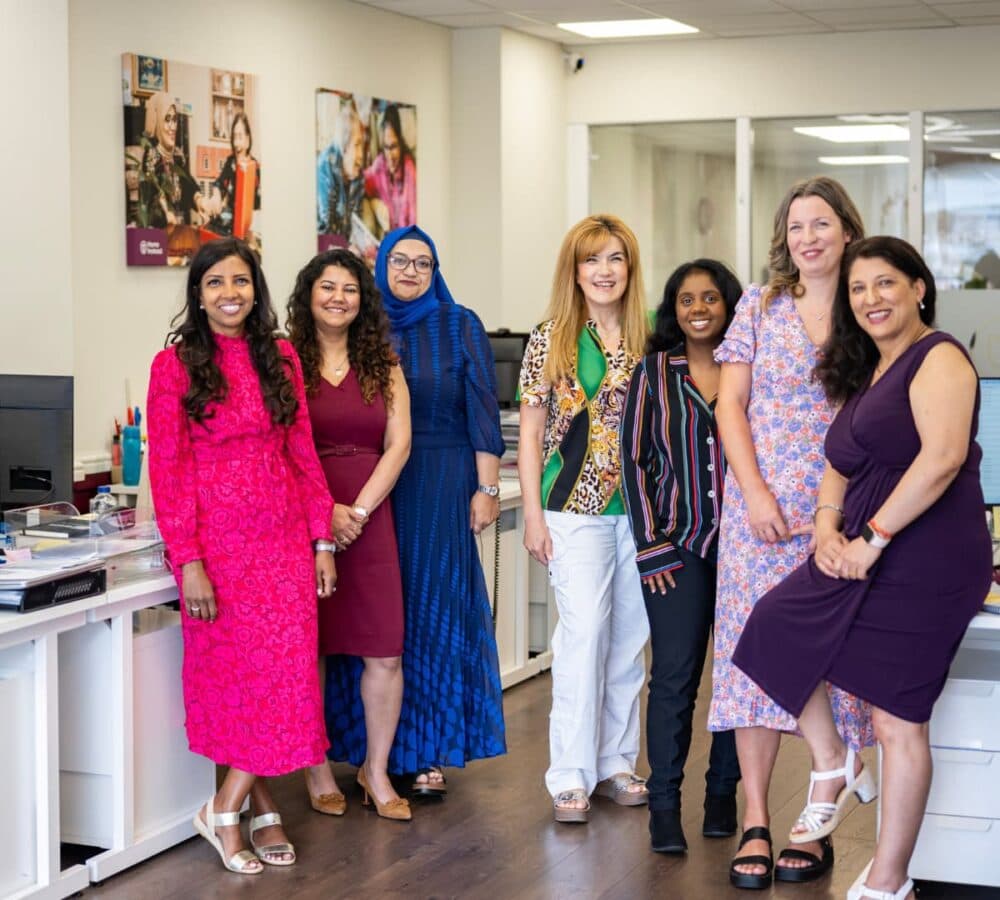 Group of women all happy and smiling and standing inside the office