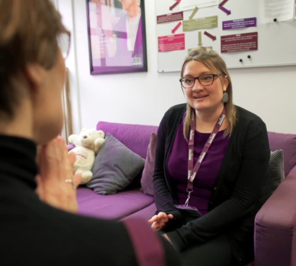 Woman sitting on a couch and wearing eyeglasses with medium length hair interviewing inside the office