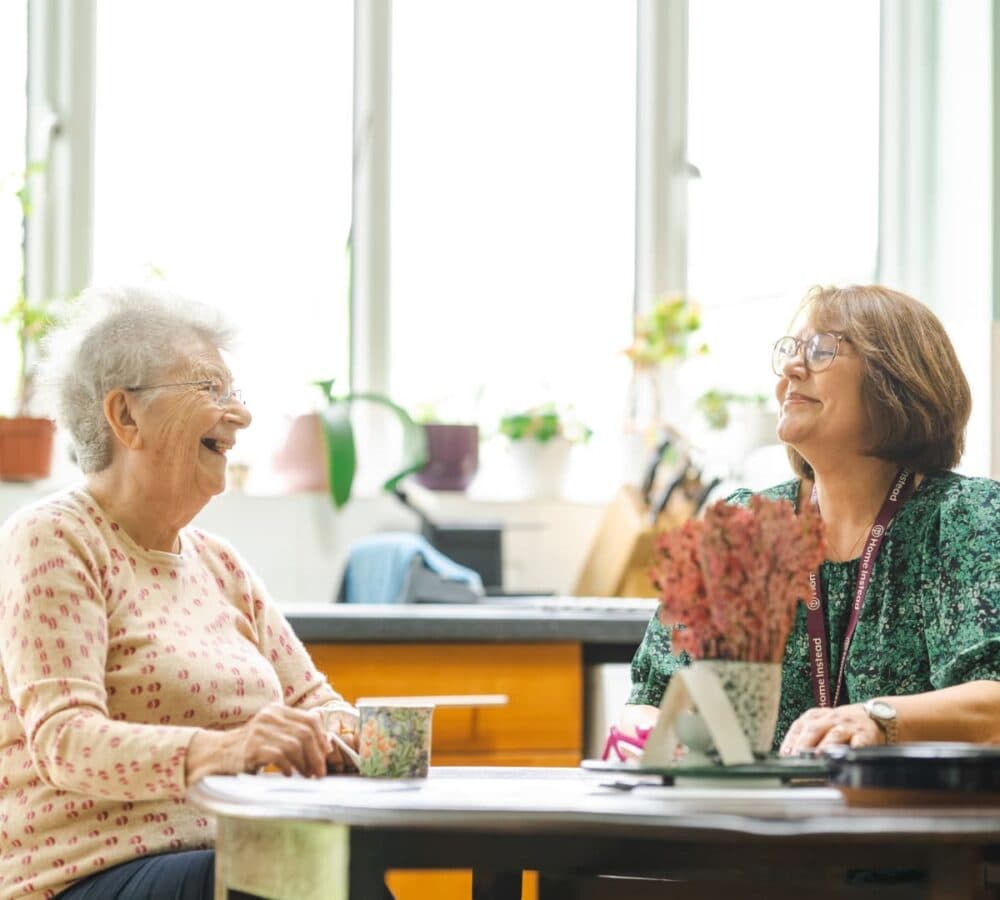 Two women in the kitchen while sitting on a chair and having a cup of coffee in the kitchen