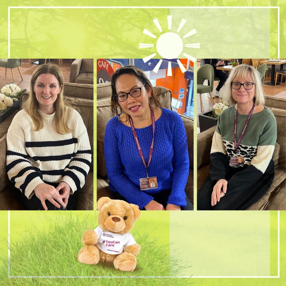 Three women sitting indoors and smiling, with a teddy bear on grass in the foreground under a sun graphic. - Home Instead