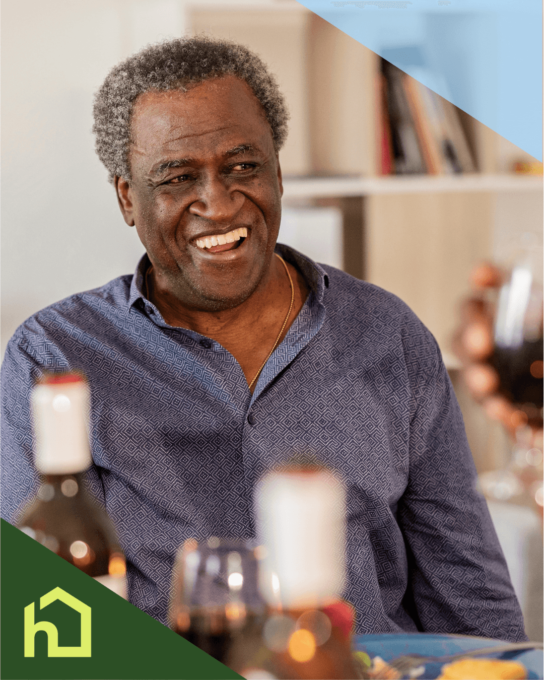 Smiling older man sitting at a table with wine bottles and glasses, in a warmly lit indoor setting. - Home Instead