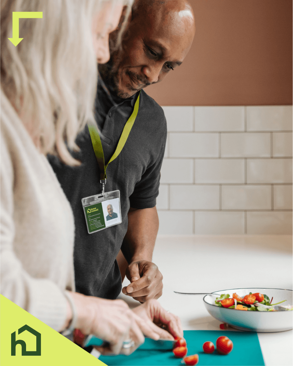 Two people chopping vegetables together in a kitchen, one wearing an ID badge and smiling. - Home Instead