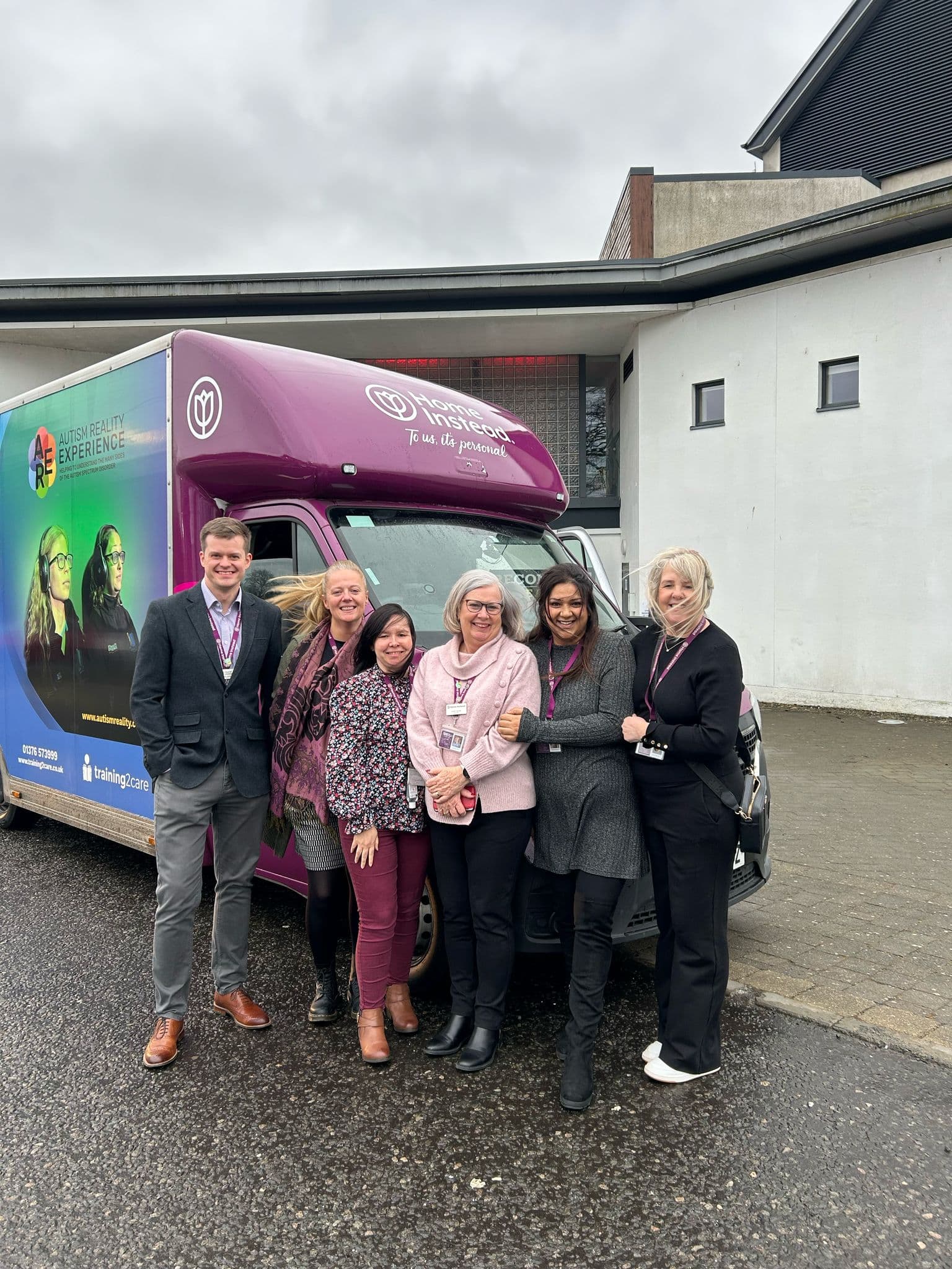 Group of Home Instead employees standing in front of a Home Instead branded dementia bus at Howden Park Centre, Livingston
