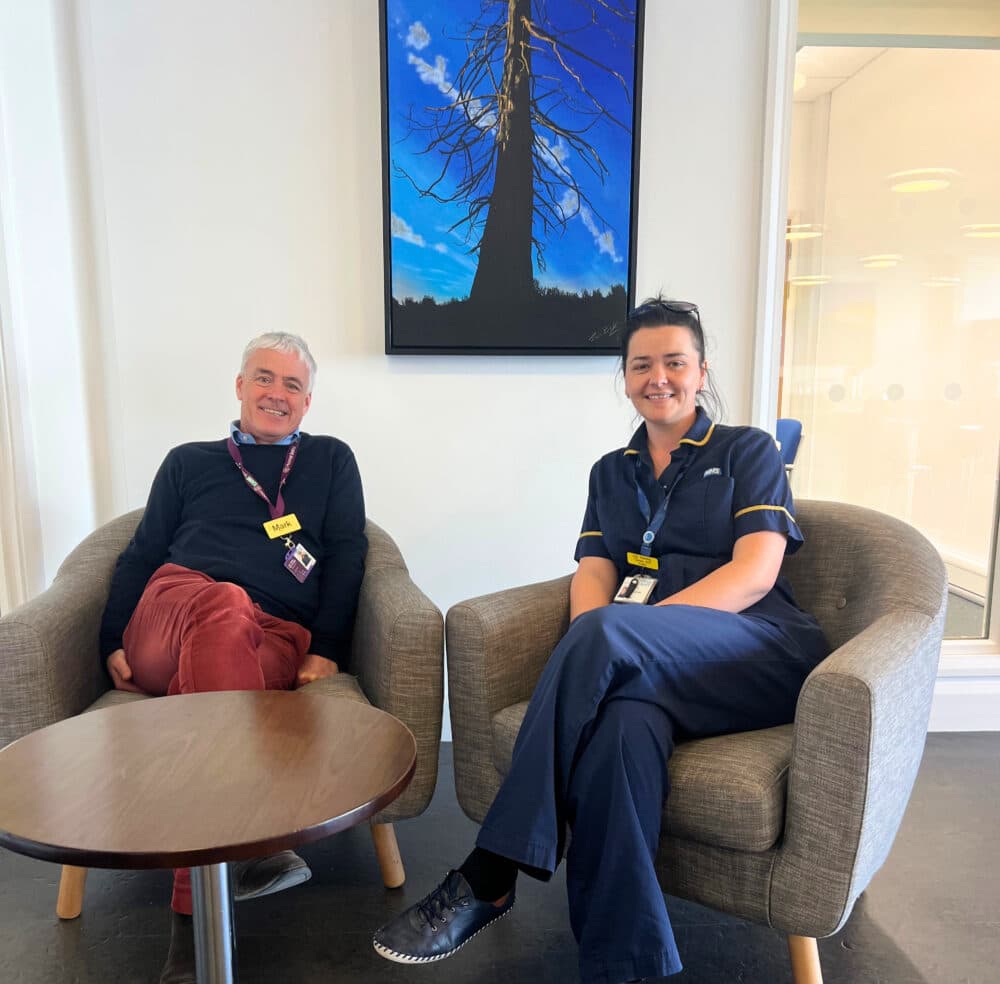 Mark and Lilly looking at the camera, sitting in chairs